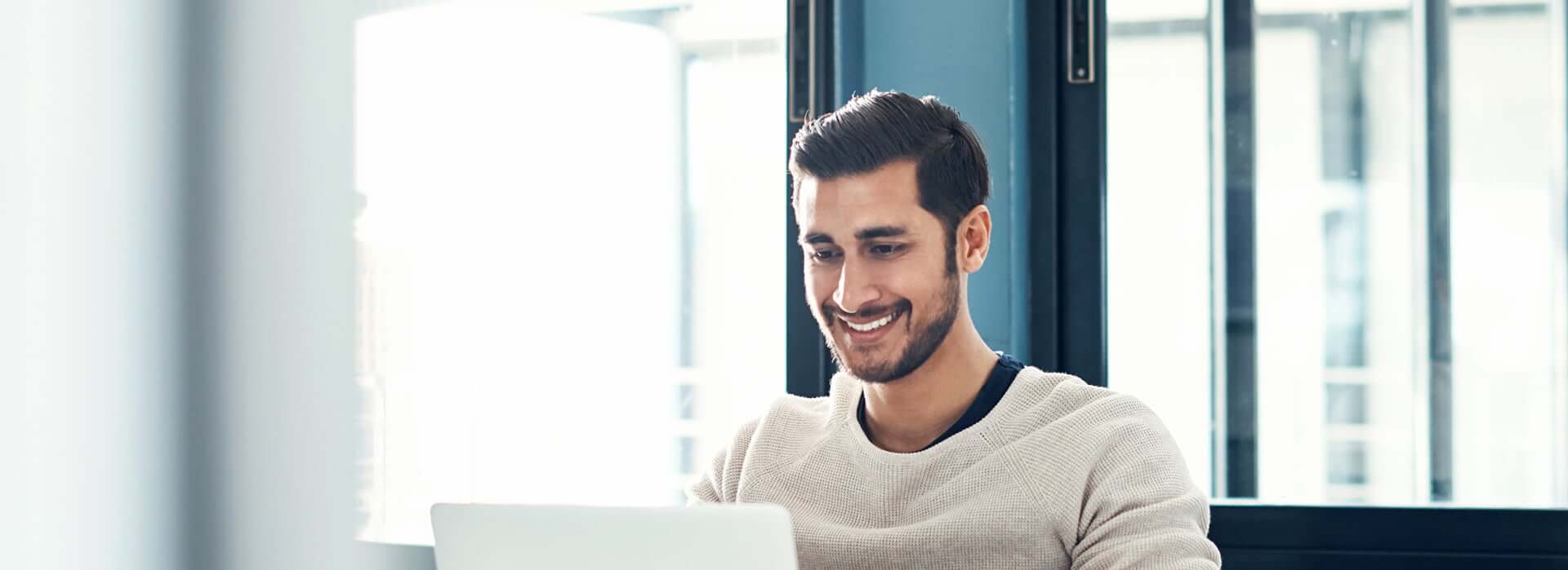 smiling man looking at his laptop