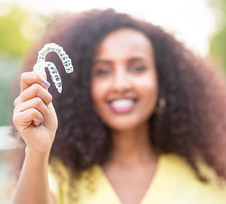woman holding up a set of clear aligners