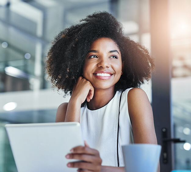 smiling woman sitting at her desk with a cup of coffee